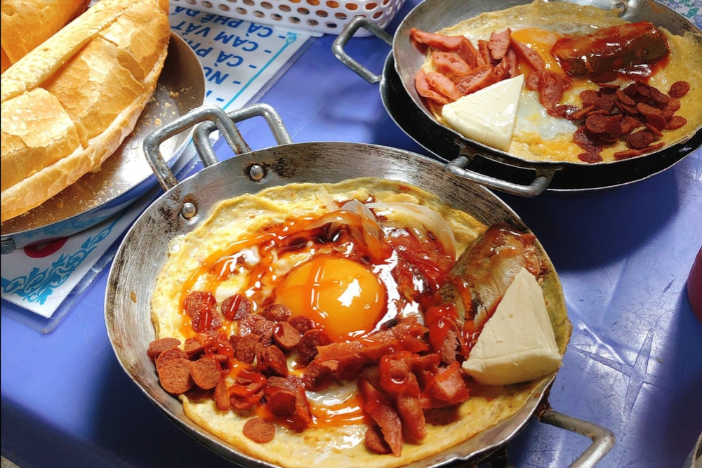 The highlight of the dish is the combination of two types of eggs and two types of sausages, served in a sizzling hot pan